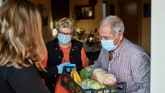 Grandchild delivers groceries to grandparents during pandemic at their home - stock photo