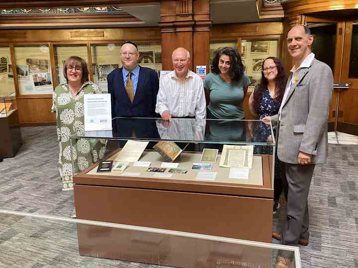 Group of 6 people stood behind a glass exhibition case