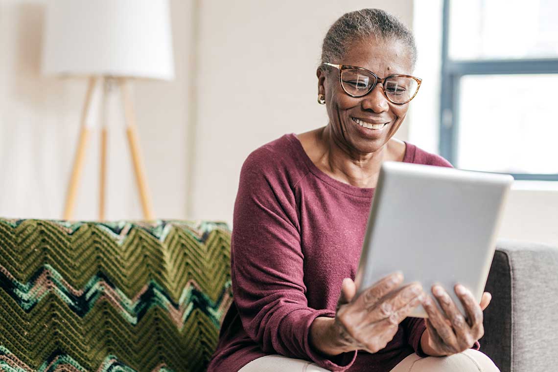 An older woman using her iPad and smiling