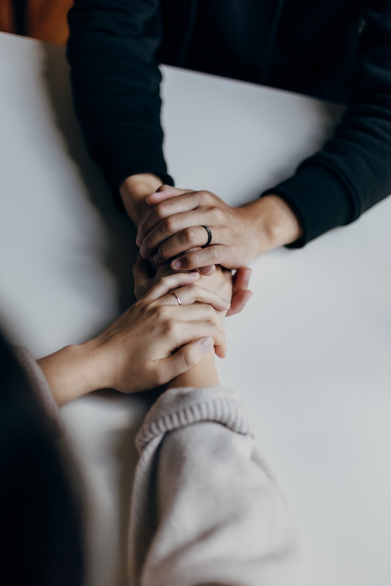 two people holding hands supportively.